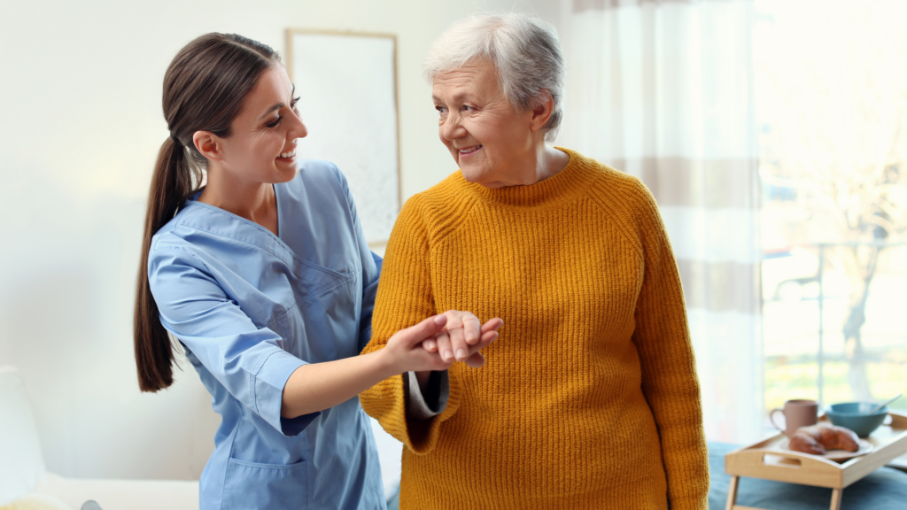 home care nurse helps elder walk by holding her hand