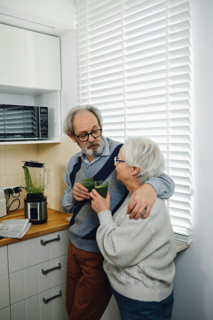 Senior couple sharing a healthy smoothie in their cozy kitchen, fostering warmth and togetherness.