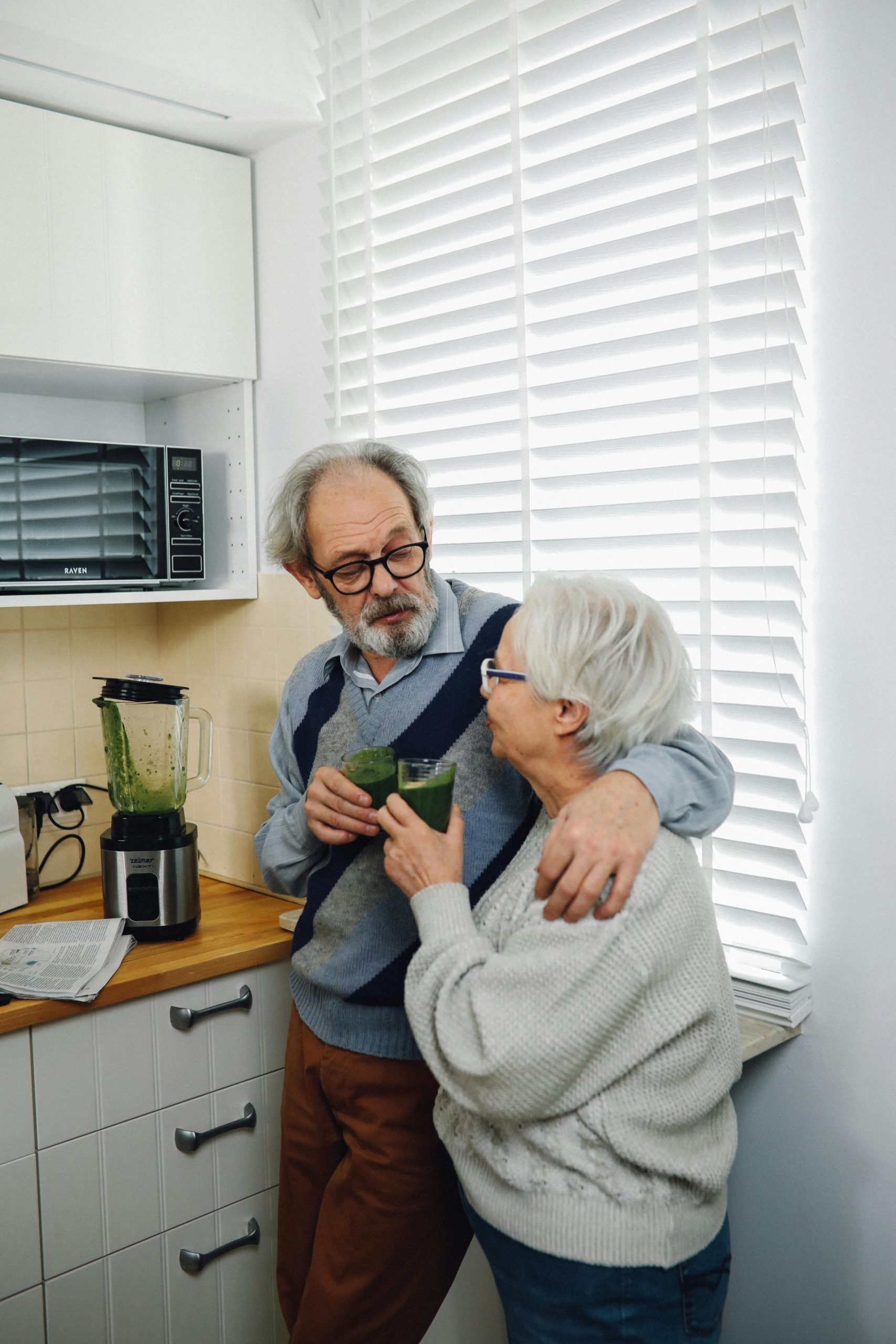 Senior couple sharing a healthy smoothie in their cozy kitchen, fostering warmth and togetherness.